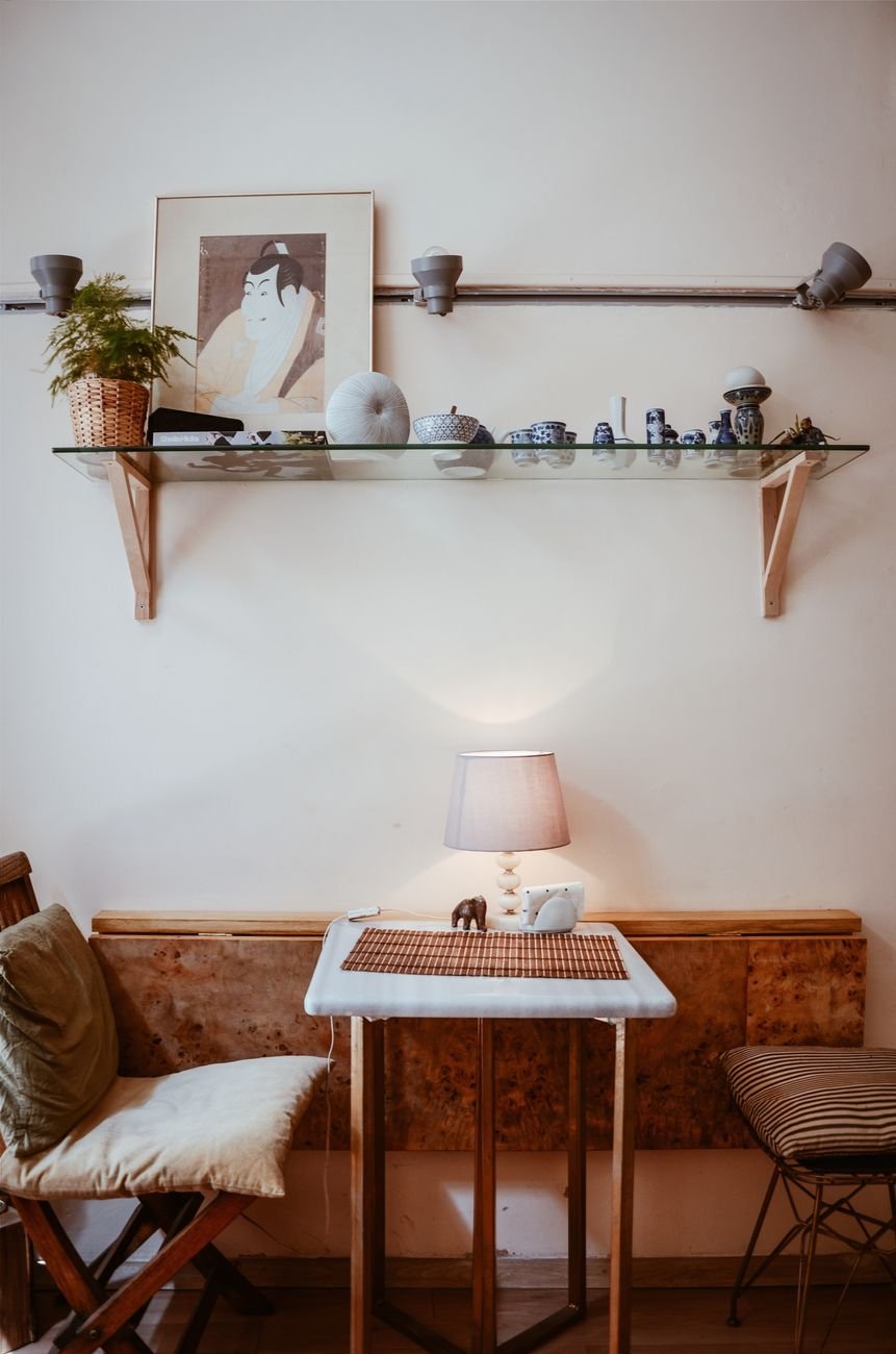 A cozy and modern living room featuring a decorative shelf, chairs, and a lamp on a wooden table