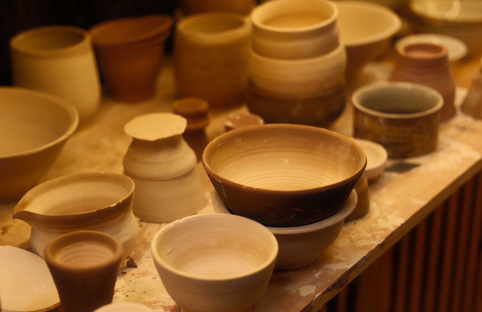 A collection of handcrafted ceramic bowls displayed in an artisan pottery studio with soft lighting